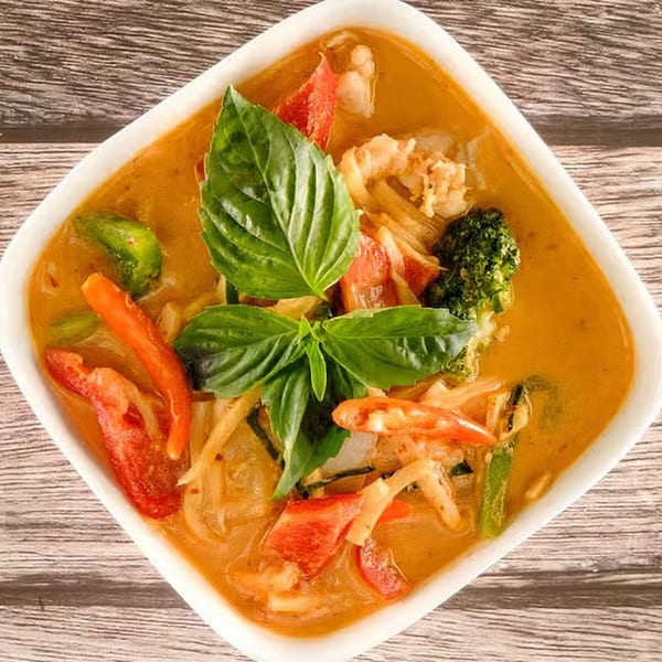 Tasty Thai Tampa's red curry with shrimp, vegetables, and basil in a white bowl.