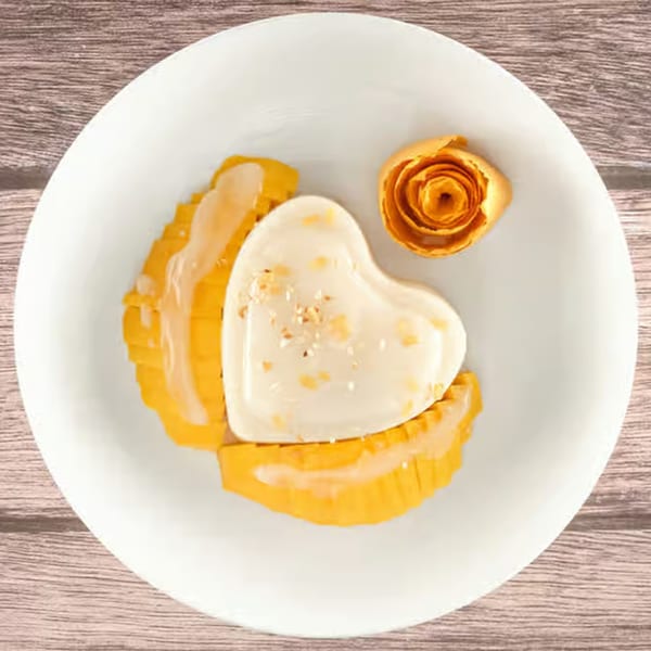 Heart-shaped dessert with mango slices and a mango rose on a white plate from Tasty Thai Tampa.