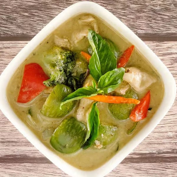 Tasty Thai Tampa's green curry with chicken, broccoli, red peppers, and basil in a white bowl.