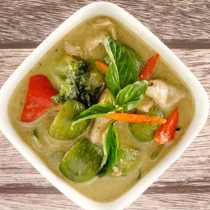 Tasty Thai Tampa's green curry with chicken, broccoli, red peppers, and basil in a white bowl.