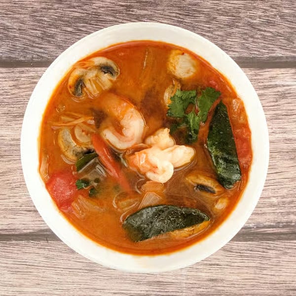 A bowl of Tom Yum soup from Tasty Thai Tampa, with shrimp, mushrooms, and herbs.