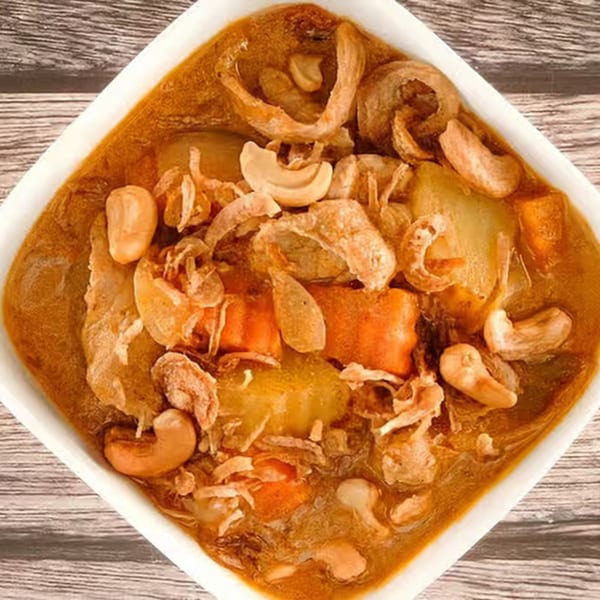 Tasty Thai Tampa's Massaman Curry with cashews, carrots, potatoes, and fried onions in a white bowl.